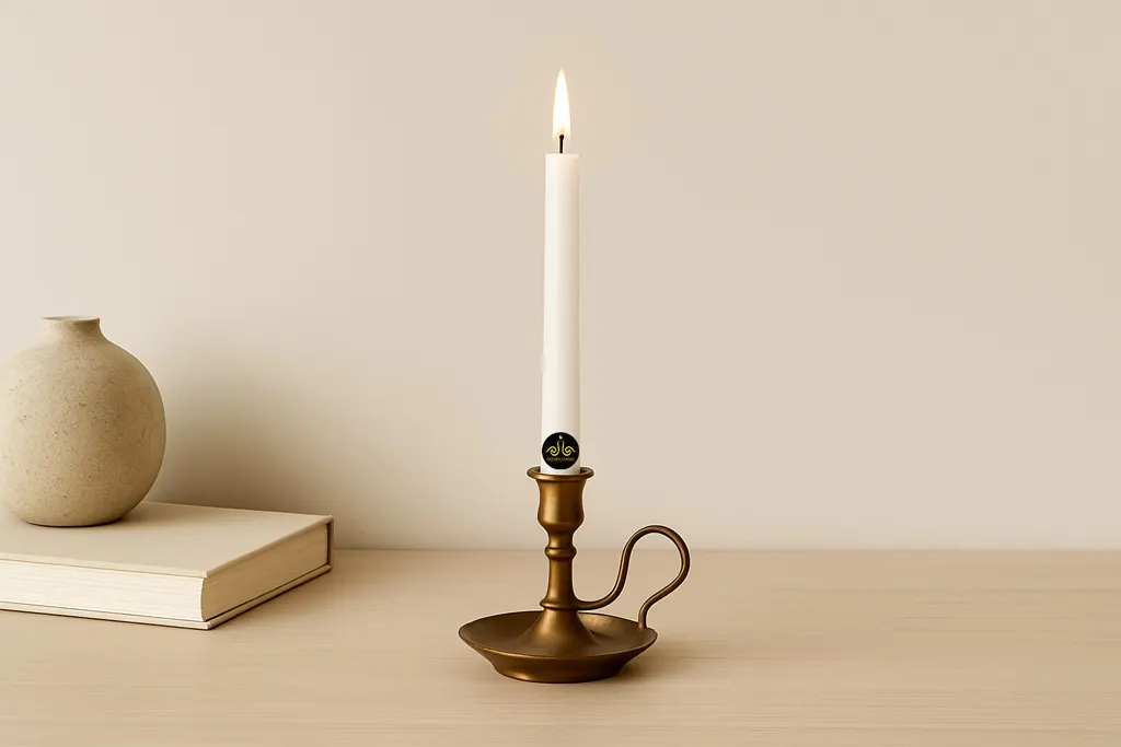 A clear wax candle burns in a beautiful brass candlestick against a milky background