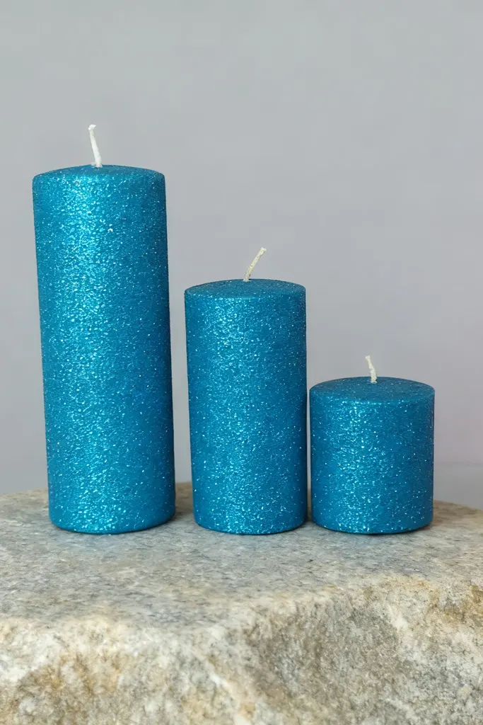 3 pillar blue glitter candles in 3 sizes stand on a stone